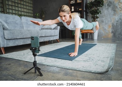 Online Yoga At Home Girl Is Engaged In Training On Skype, Performing Exercises On The Mat Fitness, The Phone Holds A Tripod, Strength Training, Hatha Yoga. High Quality Photo