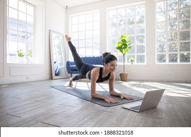 Online yoga instructor, Young Asian woman doing yoga stretching yoga at home.