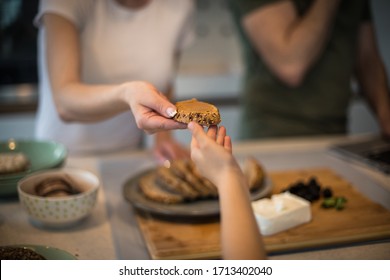 Only The Best For You. Family In Kitchen. Mother Gives Her Daughter A Slice Of Bread. Focus On Hand.