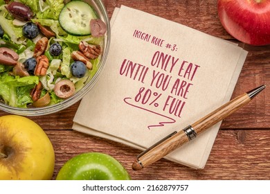 only eat until you are 80 percent full, ikigai rule, inspirational note on a napkin with a salad, healthy eating and lifestyle concept
