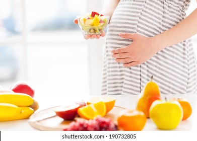 Only fresh and healthy food for my baby. Cropped image of pregnant woman holding a plate wirh fruit salad
