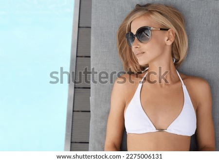 The only way to relax. an attractive blonde woman lying by a pool.