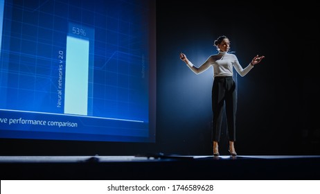 On-Stage Successful Female Speaker Presents Technological Product, Uses Remote Control for Presentation, Showing Infographics, Statistics Animation on Screen. Live Event / Device Release. - Powered by Shutterstock