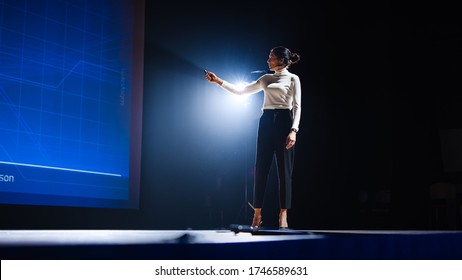 On-Stage Successful Female Speaker Presents Technological Product, Uses Remote Control for Presentation, Showing Infographics, Statistics Animation on Screen. Live Event / Device Release. - Shutterstock ID 1746589631