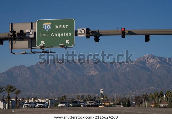 Ontario, California, USA - January\
30, 2022: image of a sign indicating the Interstate 10, I-10,\
highway shown with the San Gabriel Mountains in the background.\
