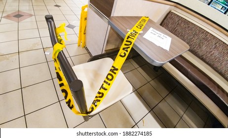 ONTARIO CANADA - DEC 12 2020: Yellow Tape With The Word Caution Placed Around Tables And Chairs Inside Tim Horton's Due To Covid-19 Pandemic.  Tim Horton's Is A Fast Food Restaurant Chain In Canada.