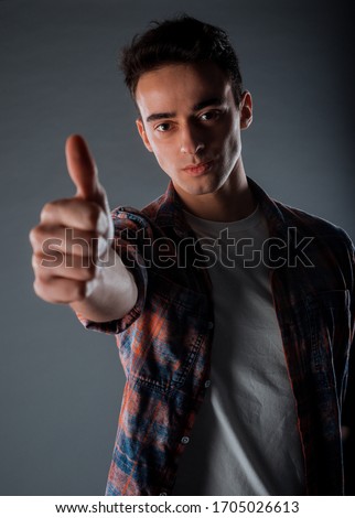 ool young man dressed in checkered shirt making a like sign