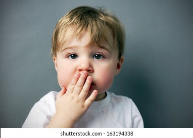 oops! cute and funny  little blond boy or toddler with hand in front of mouth