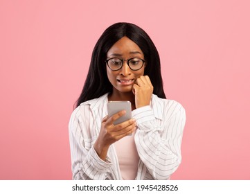 Oops. Embarassed Black Woman Looking At Mobile Phone Screen In Confusion On Pink Studio Background. Emotional African American Lady Making Mistake While Working In Web