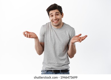 Oops sorry, my mistake. Man shrugging and smiling awkward, feeling guilty, apologizing and looking coy at camera, standing over white background - Shutterstock ID 1946473699