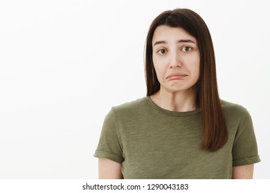 Oops, sorry. Portrait of insecure guilty and shy cute brunette wobble chin and lower lips, making shoulder shrug as making mistake, posing sad and hesitant against gray background, being shouted at - Shutterstock ID 1290043183