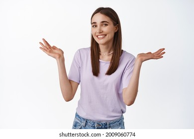 Oops Sorry Silly Mistake. Smiling Girl Shrugging Shoulders With Awkward Grin, Did Not Know, Apologizing, Looking Clueless, Has Nothing To Say, Standing Over White Background