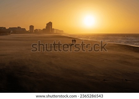 Oostende North Sea beach at sunset with people walking, West Flanders, Belgium.