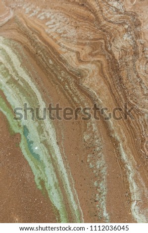 A ooze pattern on sandy beach. Wet sand of a lake shore.