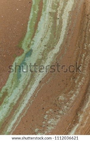 A ooze pattern on sandy beach. Wet sand of a lake shore.