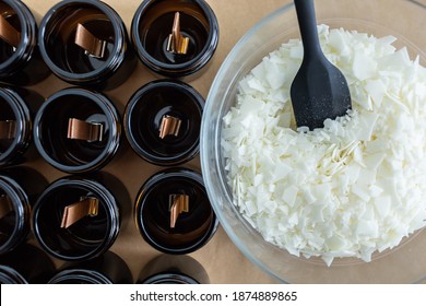 Opaque and amber candles, with wooden wick, ready to make. Soy wax not melted in a glass bowl, with a black spoon. Vegan product without animal cruelty. - Shutterstock ID 1874889865