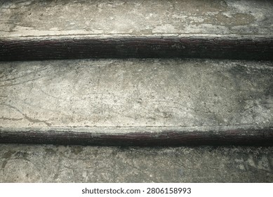 op-down close up view of weathered old concrete staircase steps with dark wooden edging showing grunge texture and abstract architectural detail