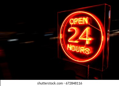 Open 24 Hours neon sign on the road side at night with moving cars. - Powered by Shutterstock