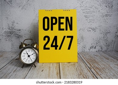 Open 24 Hrs. 7 Day Service Text Message And Alarm Clock On Wooden Background