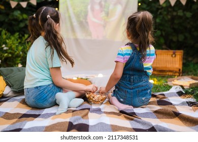 Open Air Cinema. Backyard Family Outdoor Movie Night With Kids. Sisters Spending Time Together And Watching Cimema At Backyard. DIY Screen With Film. Summer Outdoor Weekend Activities With Children.