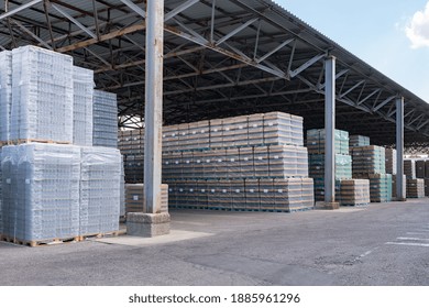 The Open Air Storage And Carriage Of The Finished Product At Industrial Facility. A Glass Clear Bottles For Alcoholic Or Soft Drinks Beverages And Canning Jars Stacked On Pallets For Forklift.