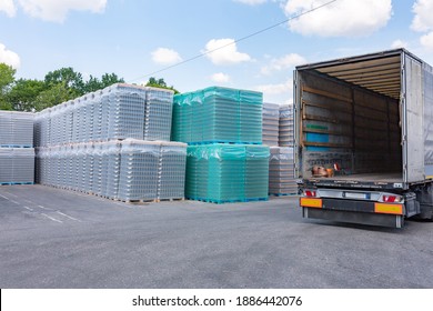 The Open Air Storage And Carriage Of The Finished Product At Industrial Facility. A Glass Clear Bottles For Alcoholic Or Soft Drinks Beverages And Canning Jars Stacked On Pallets For Forklift.