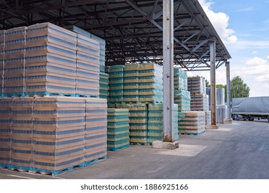 The Open Air Storage And Carriage Of The Finished Product At Industrial Facility. A Glass Clear Bottles For Alcoholic Or Soft Drinks Beverages And Canning Jars Stacked On Pallets For Forklift.