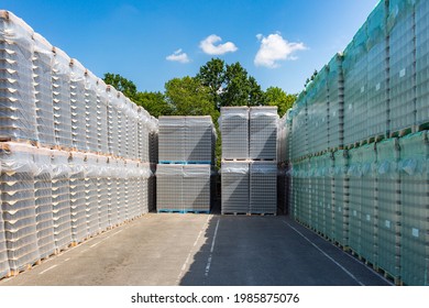 The Open Air Storage And Carriage Of The Finished Product At Industrial Facility. A Glass Clear Bottles For Alcoholic Or Soft Drinks Beverages And Canning Jars Stacked On Pallets For Forklift.