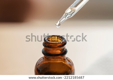 Open amber bottle with dropper pipette with serum or essential oil. Skincare products, natural cosmetic on blurred background. Medicine and beauty concept for face care. Selective focus in the center