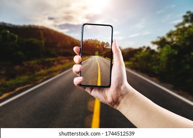 Open asphalt road through mobile phone at golden sunset and beautiful blue sky. - Powered by Shutterstock