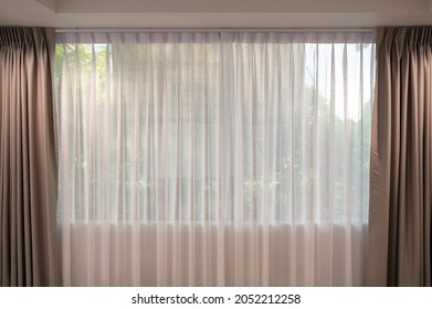 Open beige curtain with light filter fabric on window at home - Shutterstock ID 2052212258