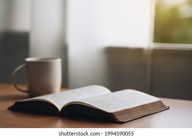Open bible with a cup of coffee for morning devotion on wooden table with window light.book and coffee cup on wooden table. - Shutterstock ID 1994590055