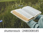 Open bible in hands close-up, concept of calmness and morning solitude.