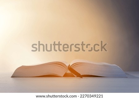 Open Bible on white wooden table against beige background. Space for text