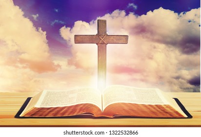 Open Bible On Wooden Table Over The Light Through Dark Cloudy Sunset Sky. Christian Concept Show The Word Of God Is The Light Of Mandkind