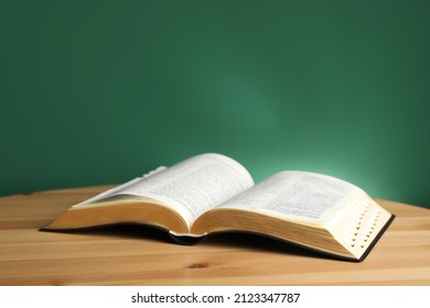 Open Bible On Wooden Table Against Green Background