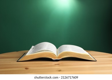 Open Bible On Wooden Table Against Green Background