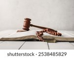 Open Bible with rosary beads on light wooden table