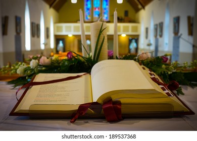 Open Bible And Wedding Flowers On The Altar In Catholic Church. Shallow DOF