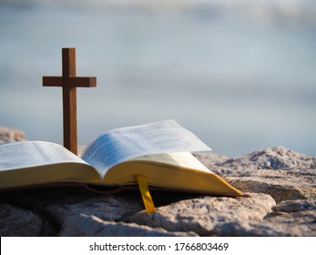 Open Bible  And Wood Holy Cross With  Blue Sea As Background. Love Study Bible , Holy Book , Christianity Concept.