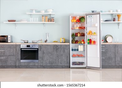Open big fridge with products in interior of kitchen - Shutterstock ID 1565367214