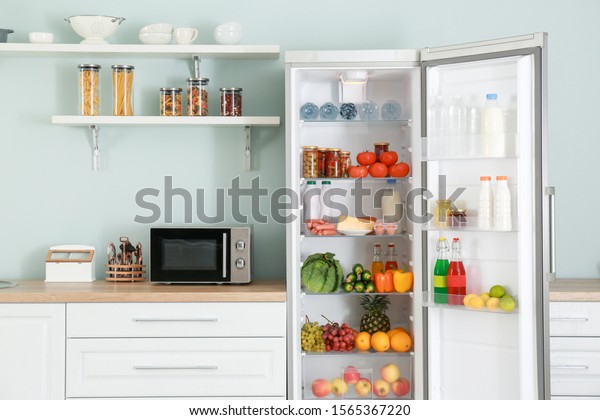Open big fridge with\
products in kitchen