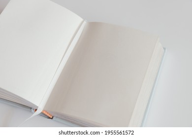 Open Blank Book On A White Background With A Bookmark. Notebook Inside Mockup. Empty Open Book In Square Format. Design Concept - Top View Of White Notebook With Blank Open