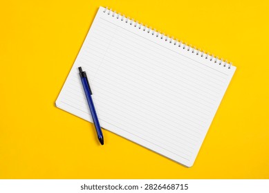 Open blank checked notepad and pen, yellow background. Mockup with copyspace.