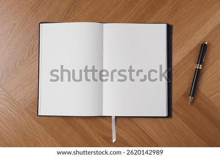 Open blank notebook and pen on wooden table, top view
