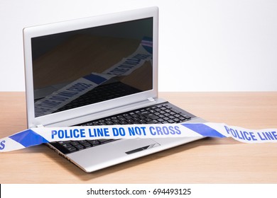 An Open, Blank Office Computer Laptop On A Plain Timber Desk With Police Crime Scene Tape Draped Across The Keyboard And A Plain White Background With Copy Space.