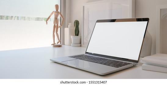 Open blank screen laptop computer in minimal workspace with cactus pots and decorations