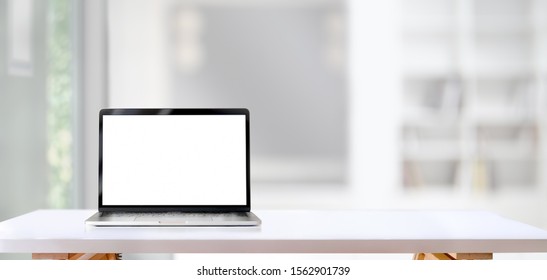 Open Blank Screen Laptop Computer On White Wooden Table With Living Room In The Background 