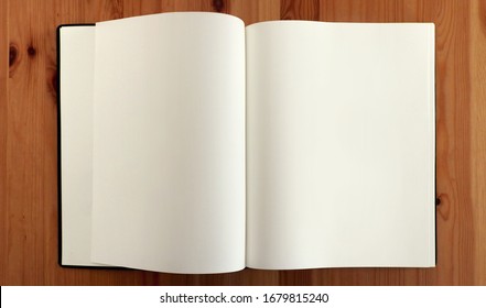 open blank sketchbook for drawing with empty curved double pages on a wooden table - education workplace desk background view from above