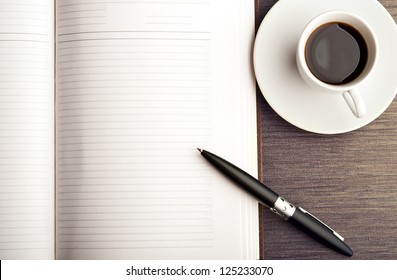 Open A Blank White Notebook, Pen And Cup Of Coffee On The Desk